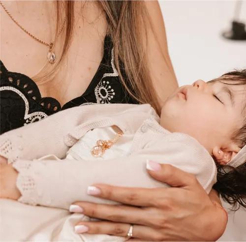 Bebé a dormir ao colo, com a roupa do batizado.