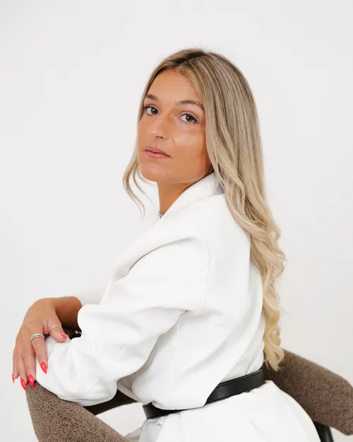 A Tatiana, de blazer branco, num retrato de estúdio.